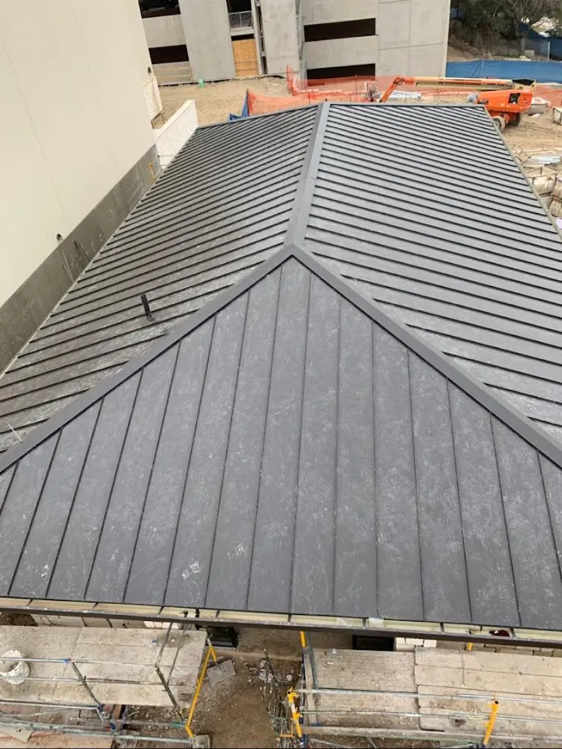 Commercial metal roof construction with crane equipment in Northborough